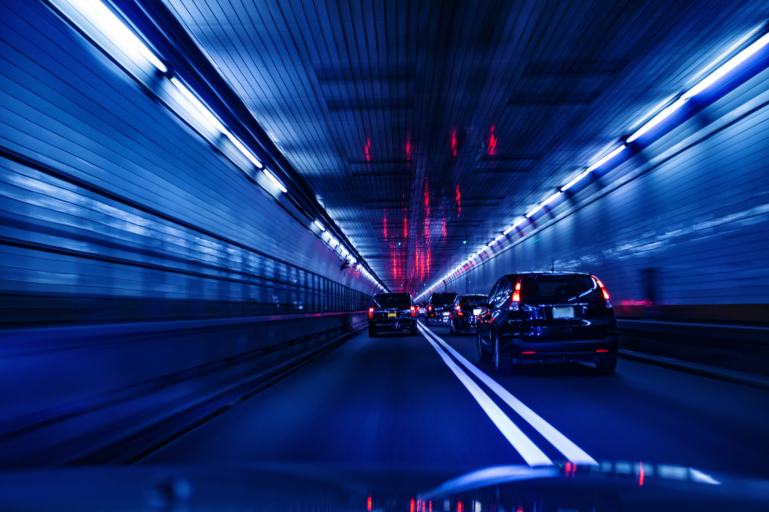 Voitures circulant dans un tunnel routier aux bandeaux lumineux bleus