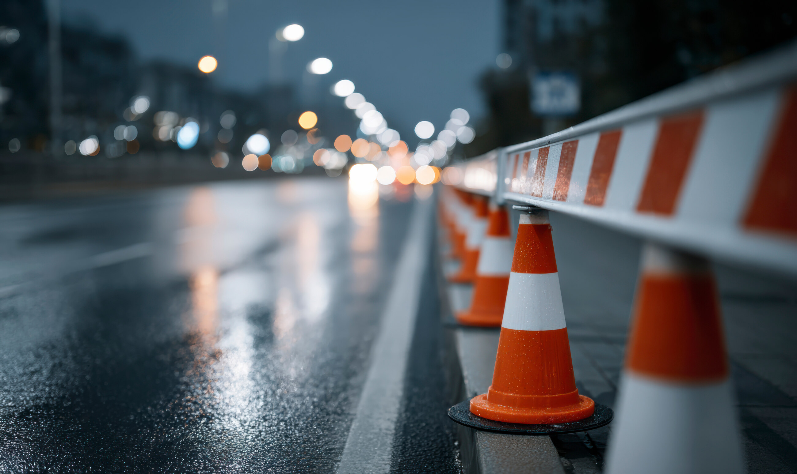 Cônes de signalisation alignés sur une chaussée mouillée de nuit